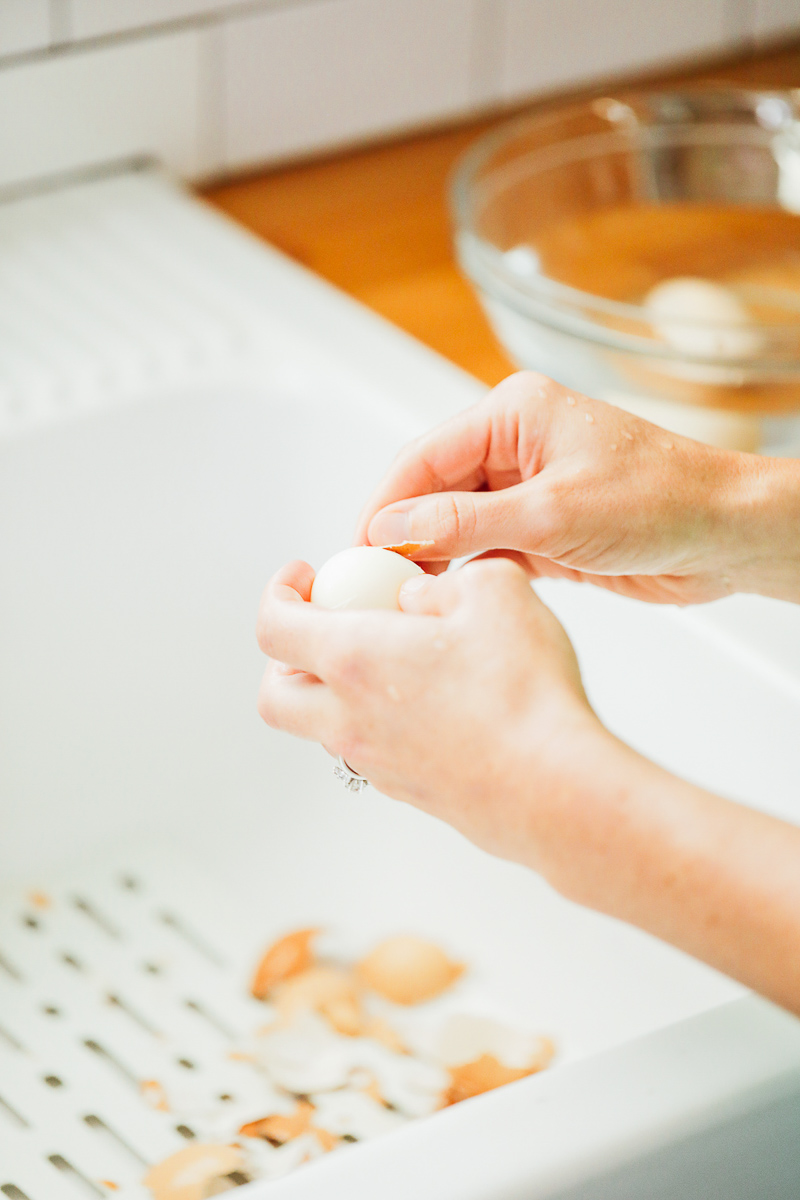 Peeling hard boiled eggs in the sink after cooking.