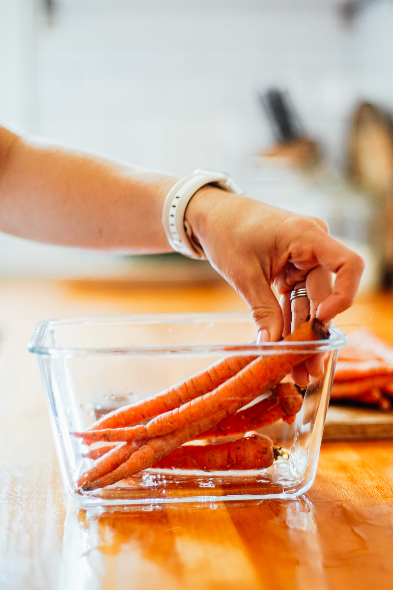 Placing whole carrots in a glass storage jar with water.