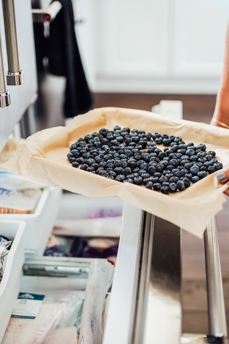 Fresh blueberries going into the freezer, on a sheet pan.