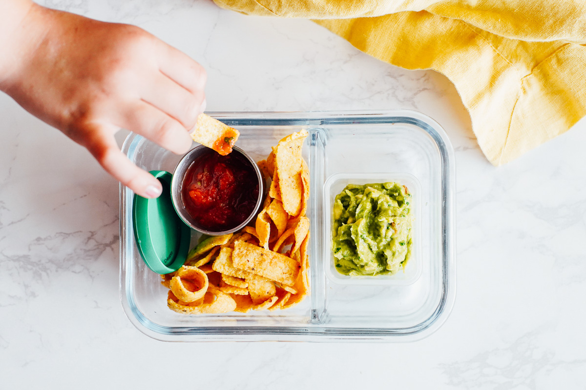 Tortilla chips, salsa, and guacamole in a snack container