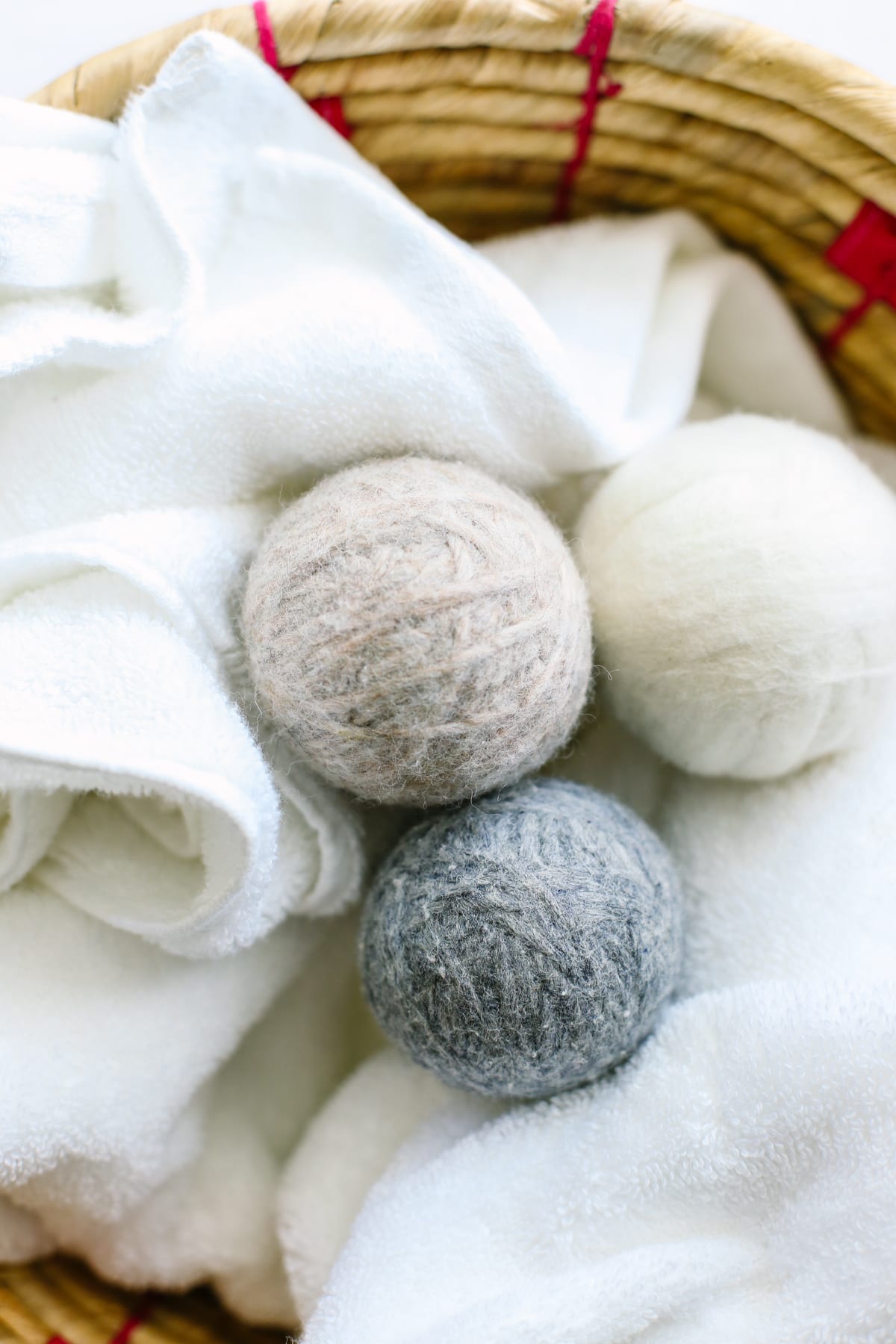 Wool dryer balls sitting in a laundry basket filled with towels.