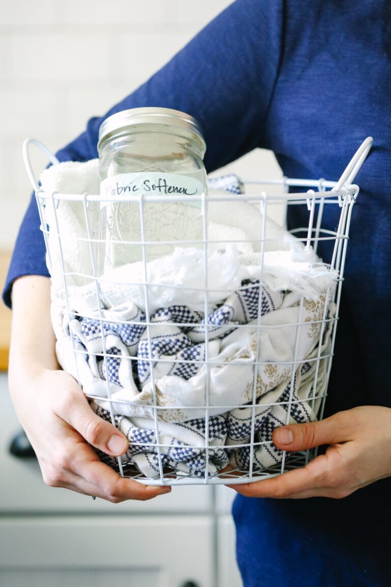 Holding a laundry basket with towels and liquid laundry fabric softener inside.