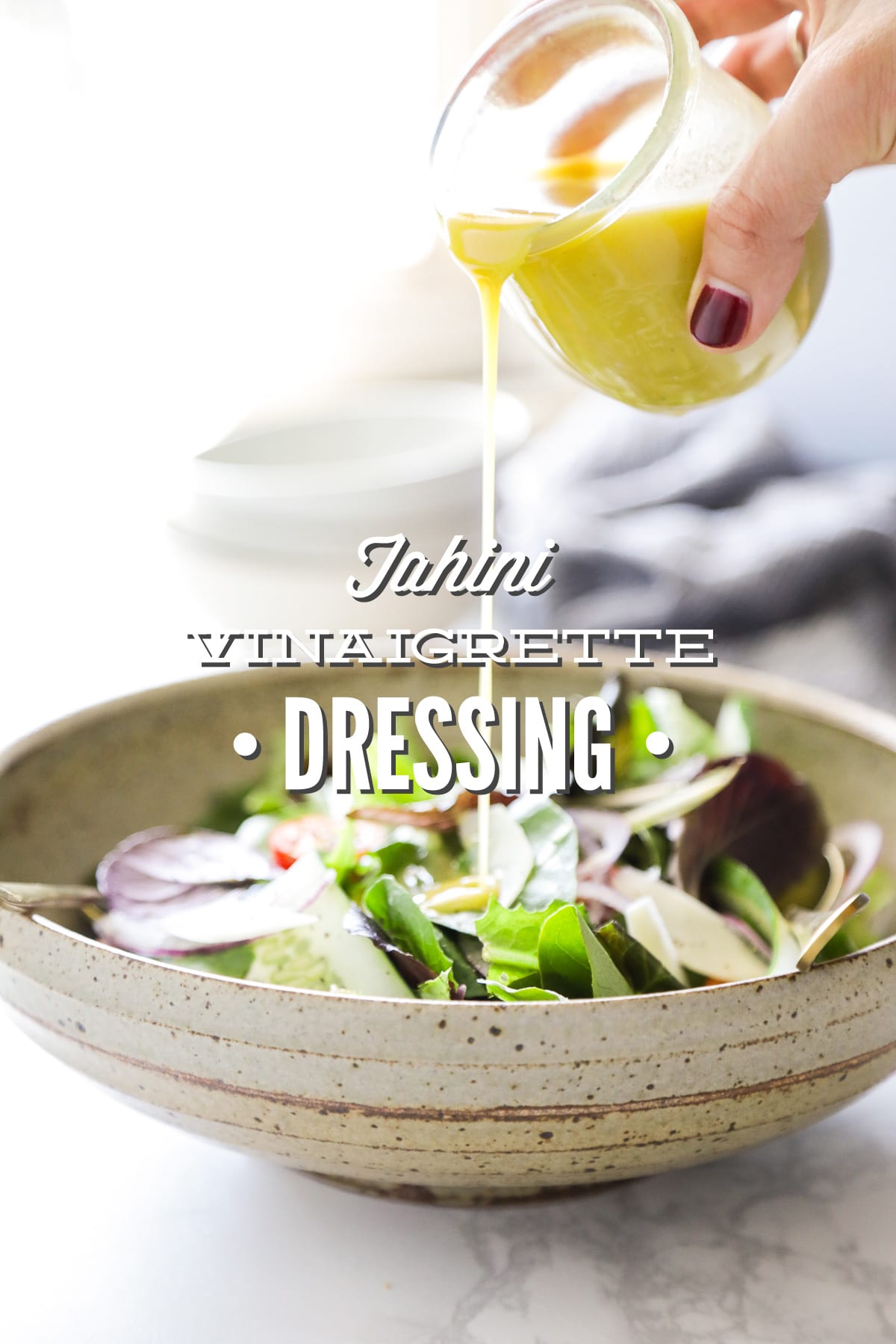 Pouring salad dressing over a leafy green salad. 