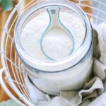 Laundry soap powder in a clear glass container with a scoop.